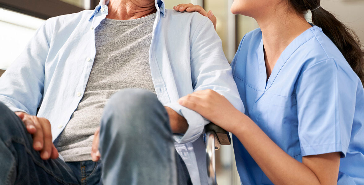 young friendly female caregiver talking to elderly man in