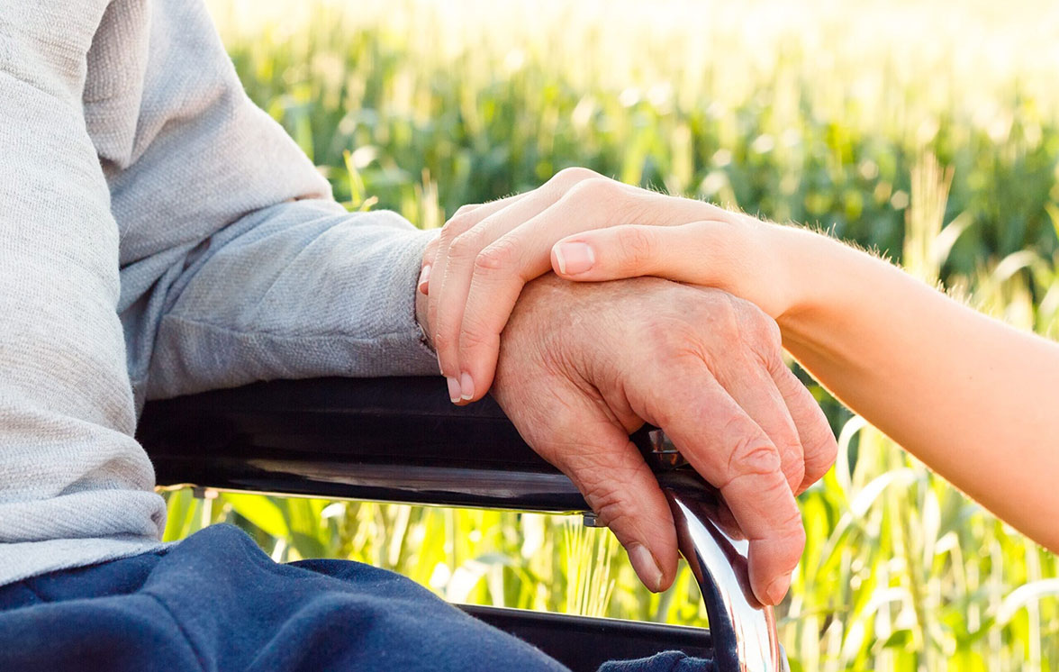 caregiver placing hand on the arm of man in wheelchair