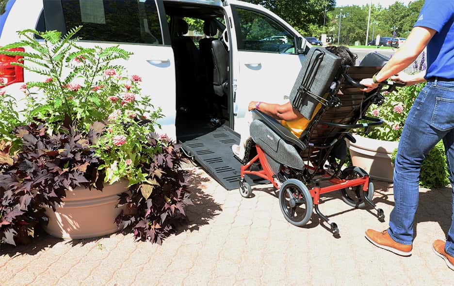 Patient in a Broda chair being wheeled into a van