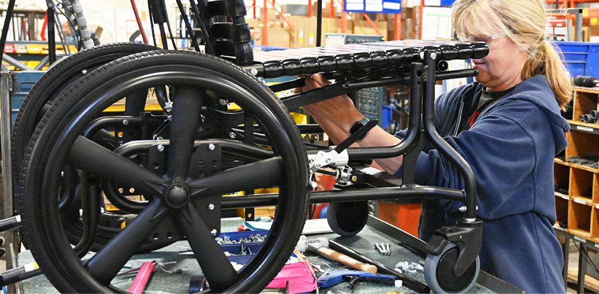 Woman adds repair parts to wheelchair in factory