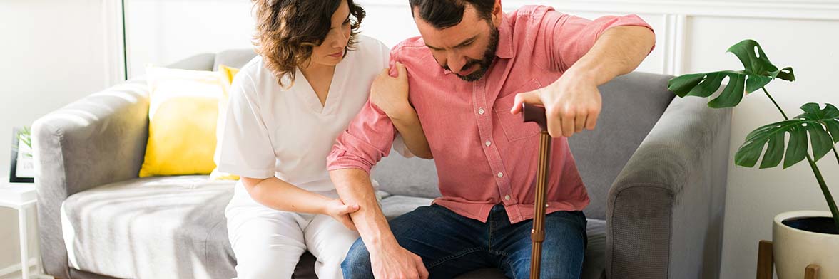 Young man with a cane standing up with a nurse at his side