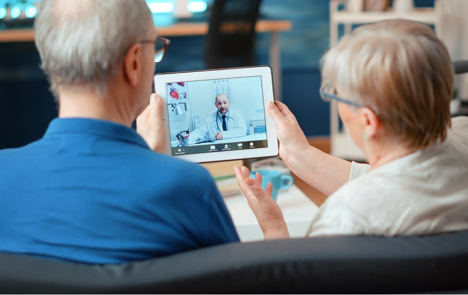 An elderly couple meets with doctor on Telehealth